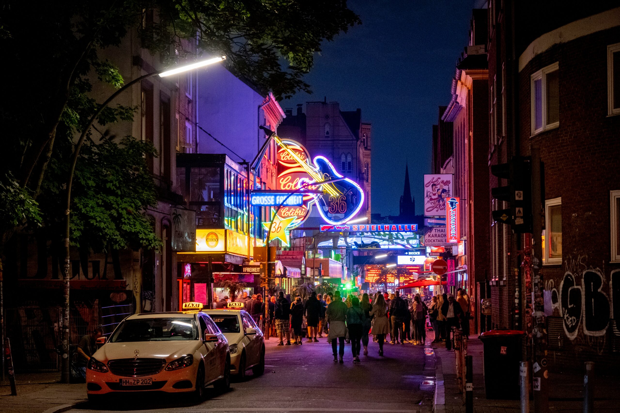 The vibrant nightlife on Hamburg’s Reeperbahn in St. Pauli, featuring neon lights, bars, and crowds enjoying the iconic party district