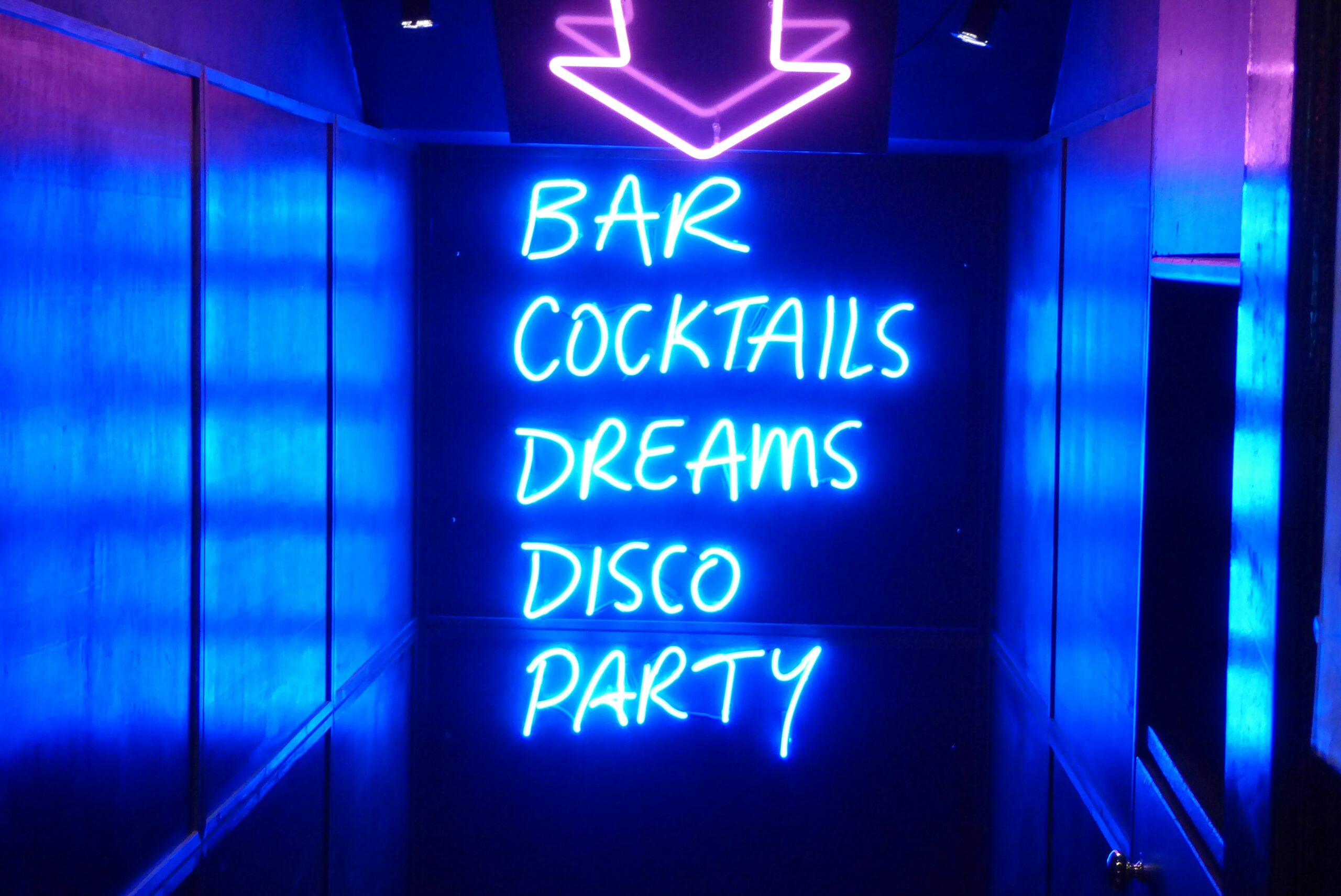 Neon sign with words ‘BAR,’ ‘COCKTAILS,’ ‘DREAMS,’ ‘DISCO,’ and ‘PARTY,’ highlighting a customized party bar tour experience in Hamburg