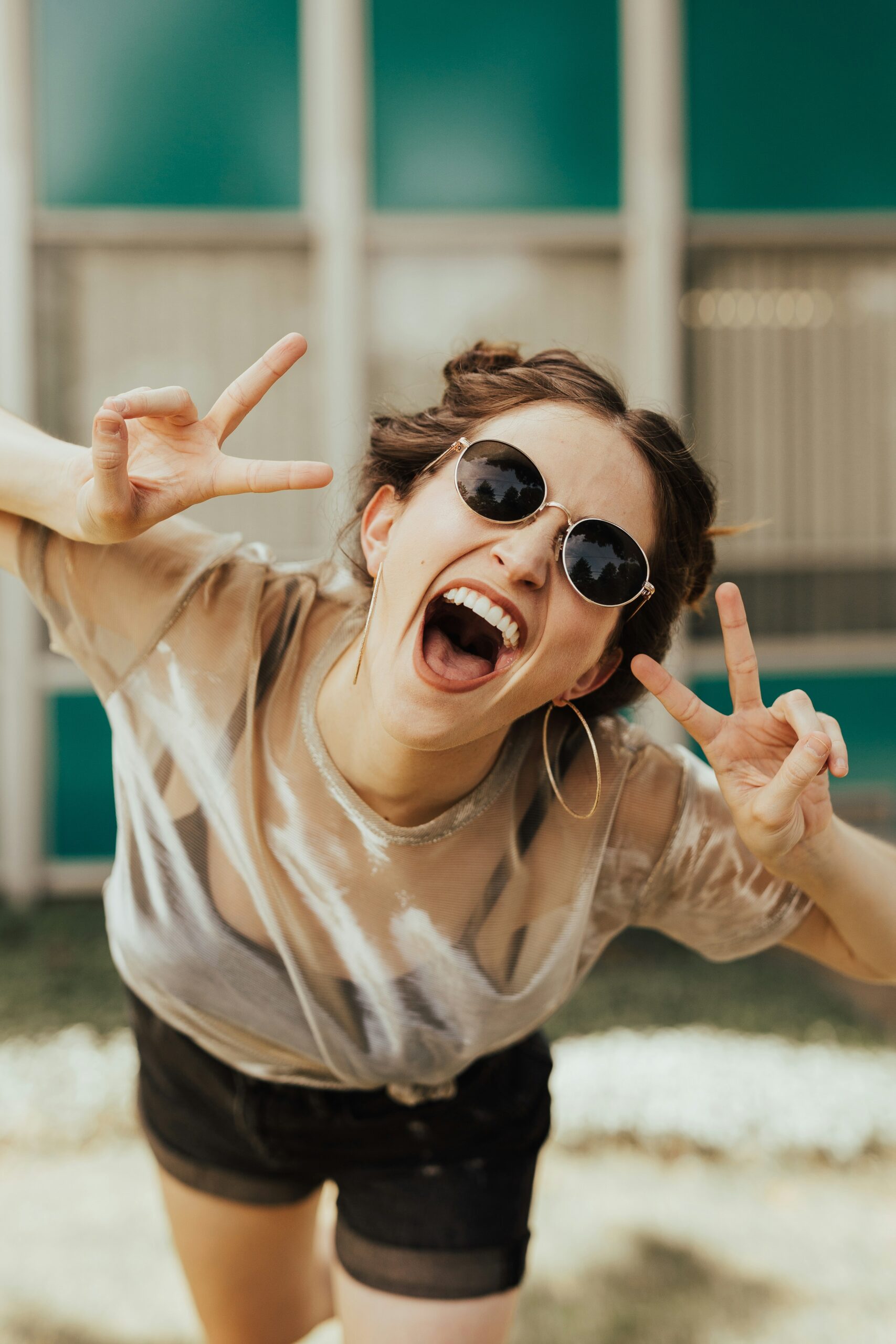 Young woman celebrating at a pub crawl in Hamburg, flashing peace signs, enjoying nightlife on the Reeperbahn in St. Pauli.