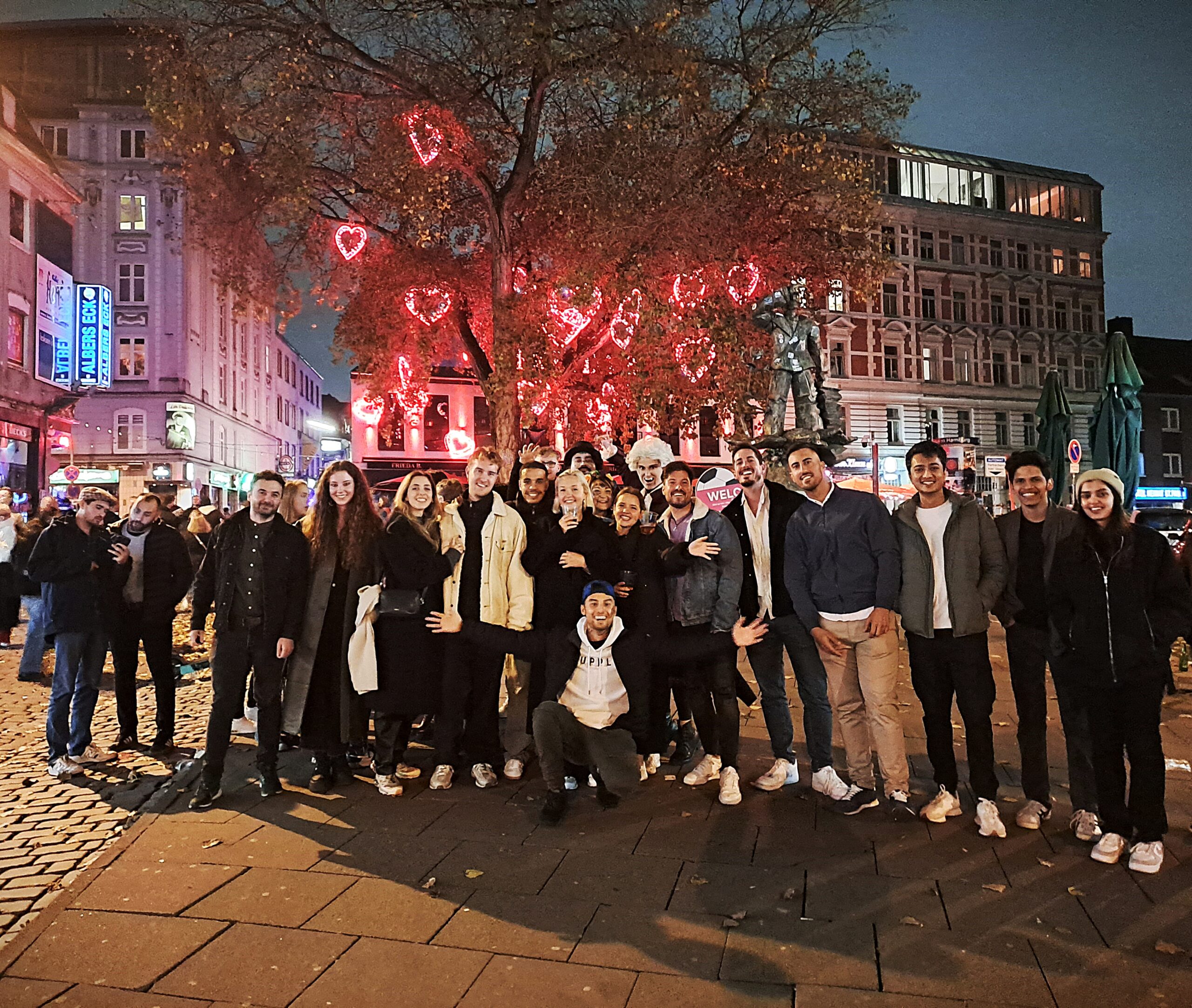 Group photo of pub crawl participants on Hamburg’s Reeperbahn in St. Pauli, enjoying nightlife and bar tour culture in Germany’s famous party district."